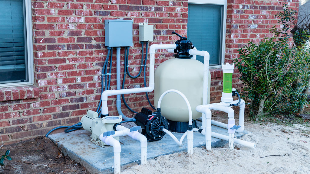 Propriétaire consultant le coffret de filtration digital dans son local technique piscine